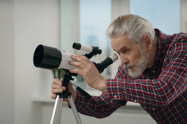 istock Senior man looking at stars through telescope in room 1743465192