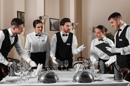 People setting table during professional butler courses in restaurant