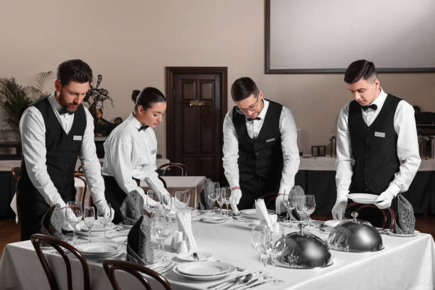 pessoas colocando mesa durante cursos de mordomo profissional em restaurante - restaurant business person setting the table clothing - fotografias e filmes do acervo