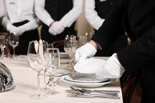 Man wearing formal suit teaching trainees in restaurant, closeup. Professional butler courses
