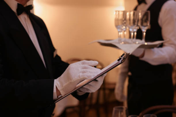 istock Man with clipboard teaching trainees indoors, closeup. Professional butler courses 1743495509