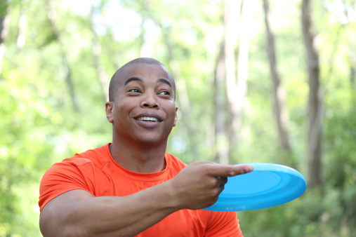 young happy man throwing frisbee outdoors
