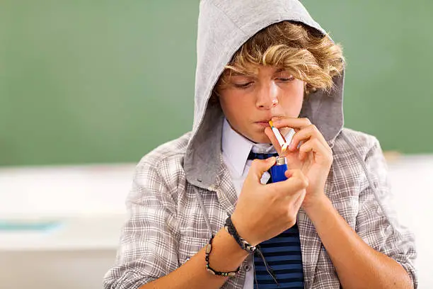 Photo of teen boy lighting cigarette