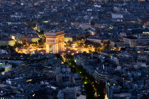 The Arc of Triumph (Arc de Triomphe) glows like a jewel in downtown Paris, France. This image was captured from a high level in the Eiffel Tower.