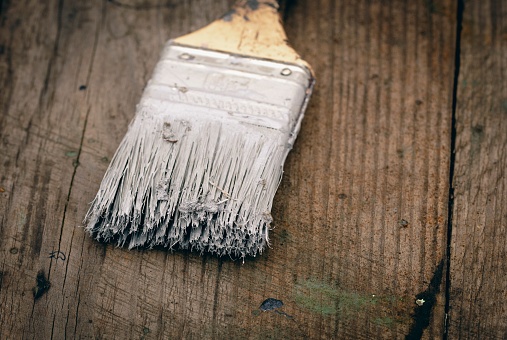 Brush covered with paint on a wooden background