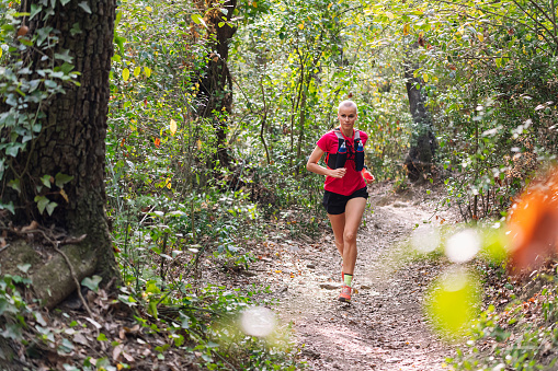 woman practicing trail running in the forest, concept of sport in nature and healthy lifestyle, copy space for text