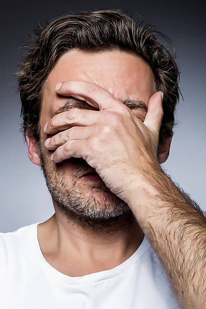 Depressed young man, covering his face stock photo