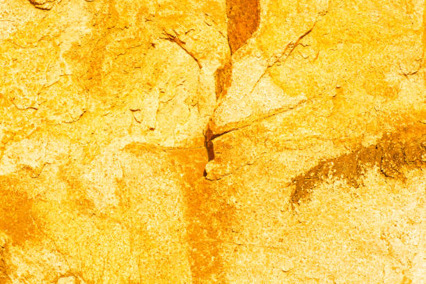 Goldstone with ripples on the surface. Defocus blurred transparent yellow colored clear calm water surface texture with the curve. Stone waves with shining pattern texture background.