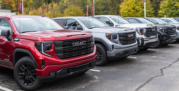 Monroeville, Pennsylvania, USA October 15, 2023 A line of GMC pickup trucks for sale at a dealership on a fall day