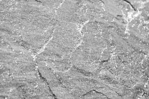 Dark rock background texture with waves surface. Dark gray stone granite background for design. Rough cracked mountain surface.