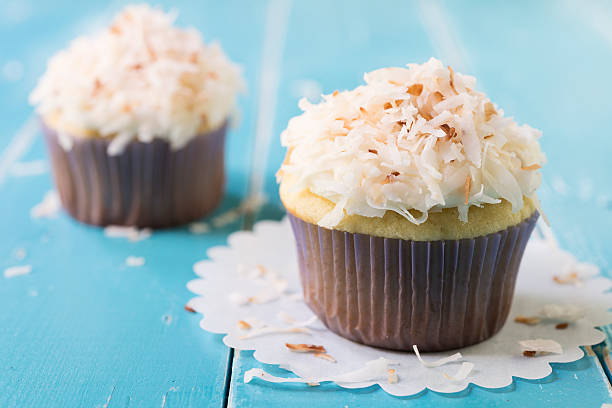 Two Toasted Coconut Topped Cupcakes on a Blue Table stock photo