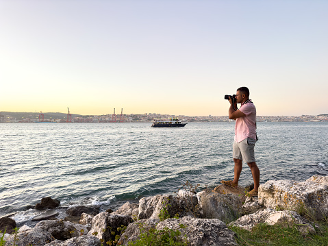 photographer photographs horizon over the sea on top of rocks