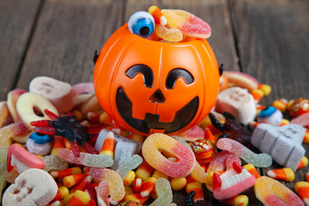 Halloween Jack o Lantern bucket filled with candy on rustic wooden table