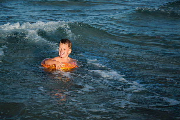 istock boy with a swim ring in the ocean waves 174374354