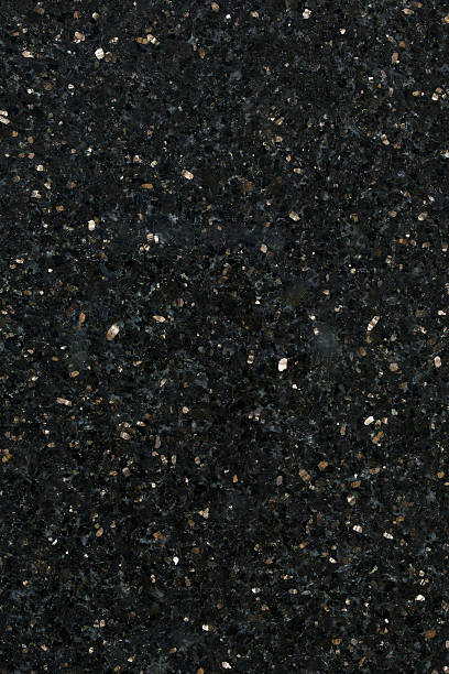 Close up of black galaxy granite building material a high definition view of Black Galaxy Granite with its virtually black background with small and medium sized flecks of bronzite or enstatite gold coloured inclusions, which add a real sparkle to this stone. A very hard and dense granite, it is used extensively for decorative purposes in kitchens, bathrooms, work tops and facades and originates from India. igneous rock stock pictures, royalty-free photos & images