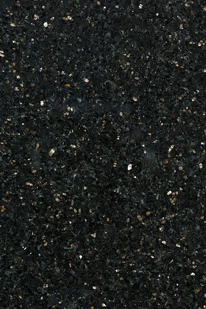 a high definition view of Black Galaxy Granite with its virtually black background with small and medium sized flecks of bronzite or enstatite gold coloured inclusions, which add a real sparkle to this stone. A very hard and dense granite, it is used extensively for decorative purposes in kitchens, bathrooms, work tops and facades and originates from India.