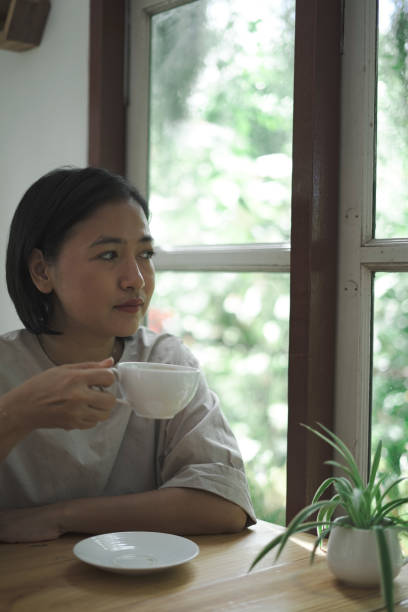 istock woman sitting drinking coffee next to the window 1743788433