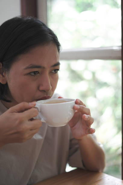 istock woman sitting drinking coffee next to the window 1743788456