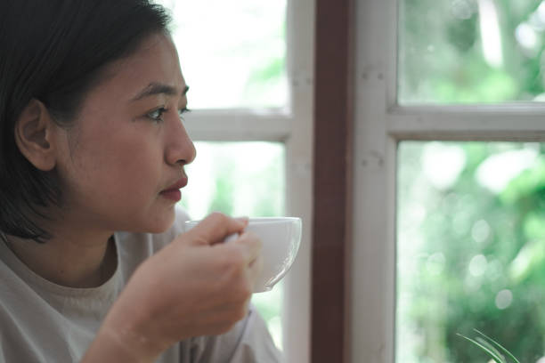 istock woman sitting drinking coffee next to the window 1743788466