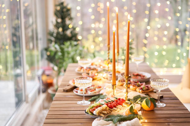 istock Christmas dinner feast. A small table is served with snacks, bruschettas, and canapes. A decorated dining table with champagne glasses, candles and christmas tree an garland in background 1743838036