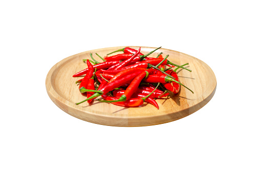 fresh red hot chili peppers on a brown wooden plate. Side view. isolated on white background with clipping path