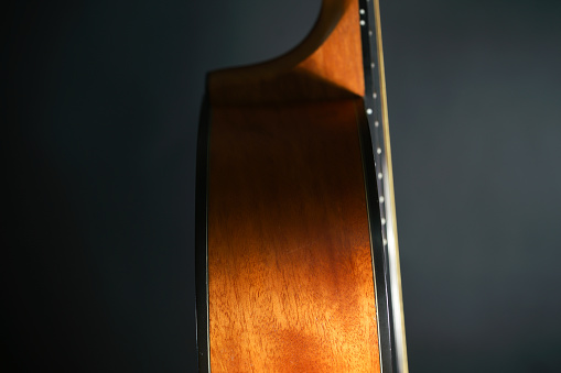 Neck with strings and body, close-up, on an old, classic acoustic guitar, under natural lighting.