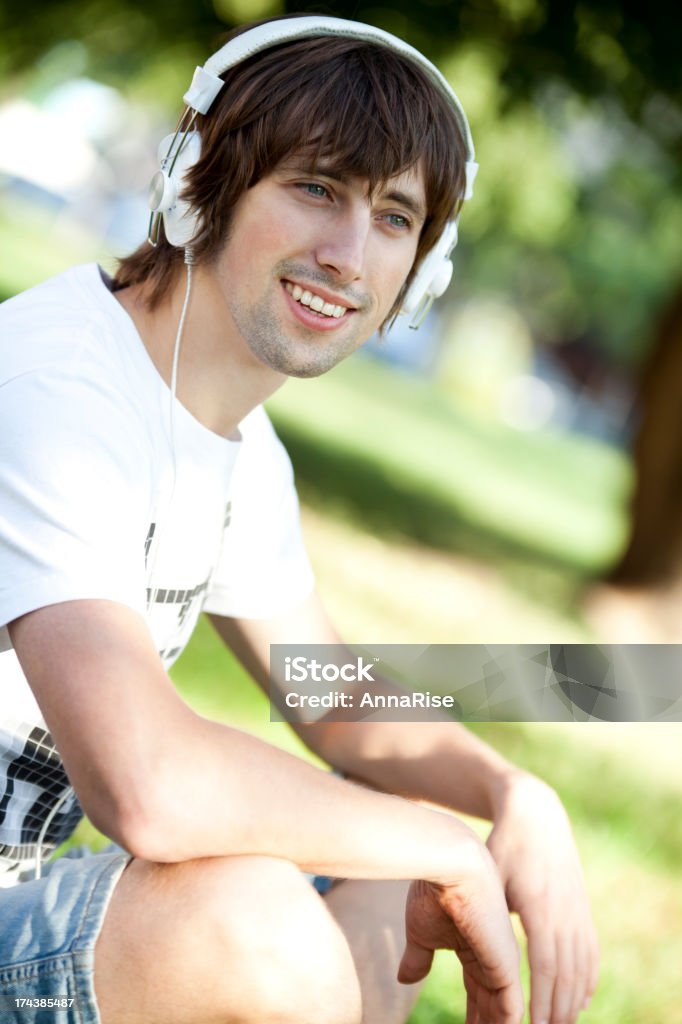 Heureux jeune homme appréciant la musique dans le parc - Photo de 25-29 ans libre de droits