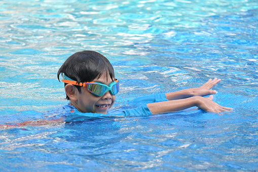 happy boy swimming in the blue pool, sport leisure activity