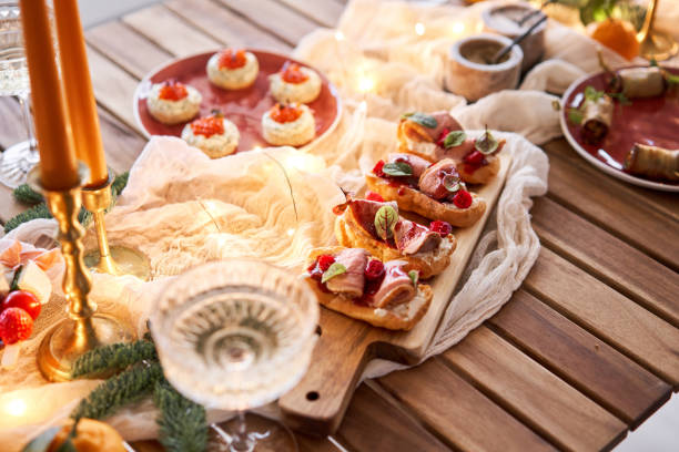 istock Christmas dinner feast. A small table is served with snacks, bruschettas, and canapes. A decorated dining table with champagne glasses, candles and christmas tree an garland in background 1743860445
