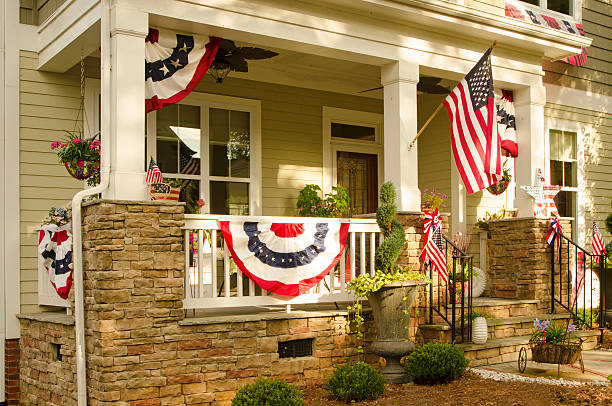 Patriotic  House Decorations Patriotic Bunting Decorations and American Flags hang from the front porch of this home in honor of the upcoming Holiday Celebration. american flag bunting stock pictures, royalty-free photos & images