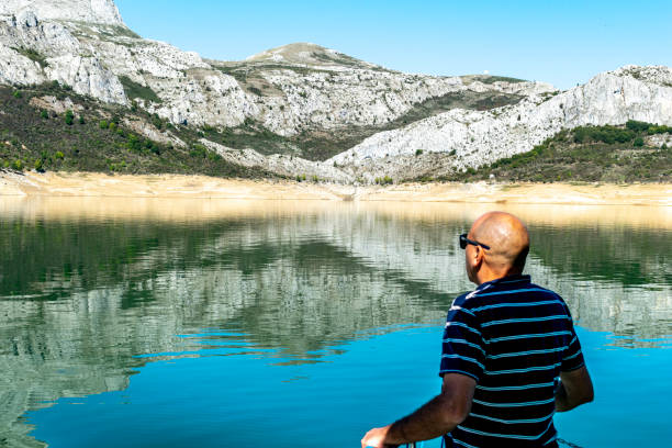 hombre contempla un precioso paisaje donde hay un lago de agua turquesa - travel destinations mountain hiking profile fotografías e imágenes de stock