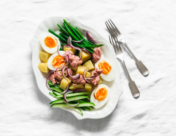 istock Breakfast plate - boiled eggs, potatoes, string beans, red onion, cucumber, canned tuna salad on a light background, top view 1743900616