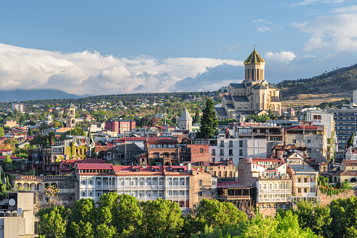 Awesome city view of Tbilisi, Georgia. The Holy Trinity Cathedral of Tbilisi (Sameba) is visible on blue sky background. The Sameba Cathedral is a popular tourist attraction of the Caucasus region.