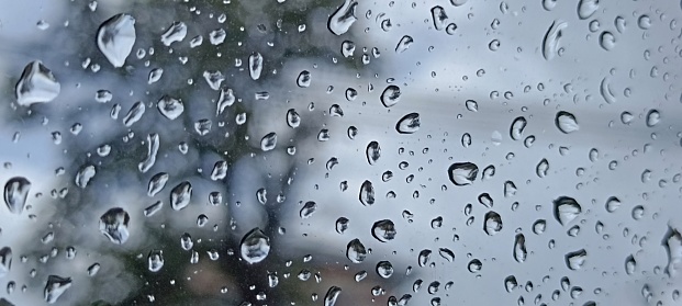 Image of rain falling against the window It is a picture of water drops and the picture outside the window is a hazy picture giving a feeling of sadness and loneliness.