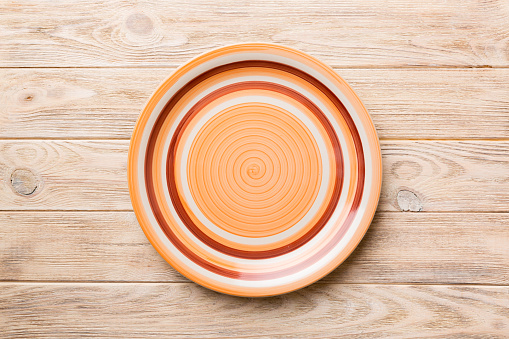 Top view of empty orange plate on wooden background. Empty space for your design.