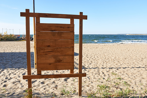 A wooden sign on the beach. Beach on the sea on a sunny day.