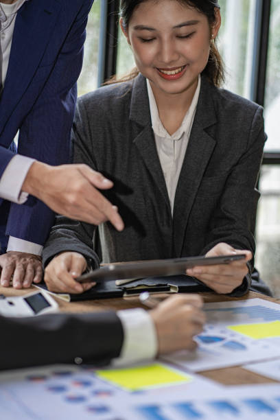 istock Young Asian accountant working in financial office, managing sales reports using calculator with laptop, preparing reports, calculating balances, documents, tax audit. vertical picture 1743951111