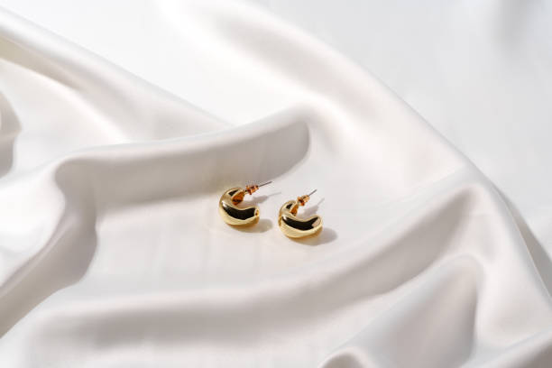 istock Golden earrings on a silk background close up 1743980349