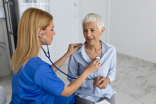 Caring female doctor use phonendoscope examine senior patient heart rate at consultation in hospital. Woman nurse or GP use stethoscope listen to woman's heartbeat in clinic.