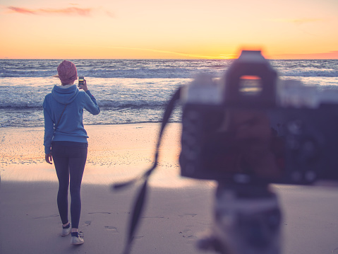 Woman photographer shooting sunset sea