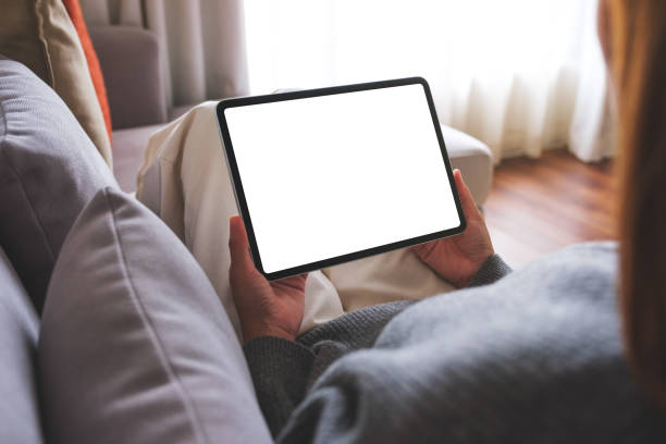 istock Mockup image of a woman holding digital tablet with blank desktop screen while lying on a sofa at home 1743995991