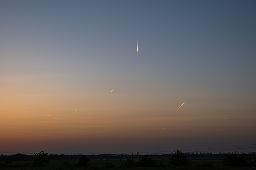 Multiple airplane jet streams in the dusk sky. Wide angle, sunset light, flat field, no people.