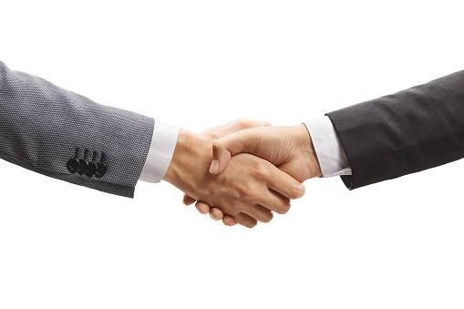 Two content businessmen sitting and shaking hands over a conference table, copy space.