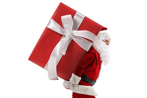 Profile shot of santa claus carrying a big preset on his back isolated on white background