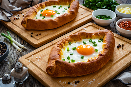 Georgian cuisine - khachapuri cheese-filled bread with fried egg on wooden background