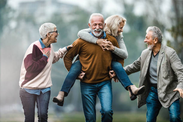 Playful mature couples having fun during autumn day in nature.