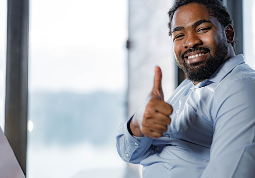 Portrait of happy black businessman showing thumbs up and looking at camera. Copy space.