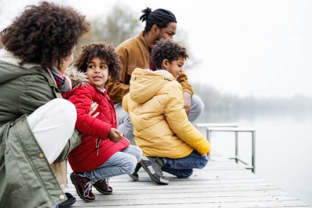 Smiling African American family relaxing on a pier at river.