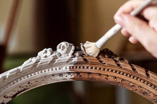 Craftsmanship, craftsman. Restoration of an antique chair, hand holds the brush with which the plaster is applied.