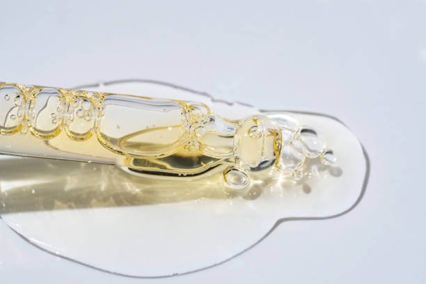 flaschenpipette pipette nahaufnahme und flüssiges gelb-oranges retinol- oder vitamin-c-gel oder serum auf blauem hintergrund - hauptspeise stock-fotos und bilder